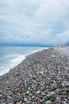 Pebble beach with gentle waves under a cloudy sky Stock Photos