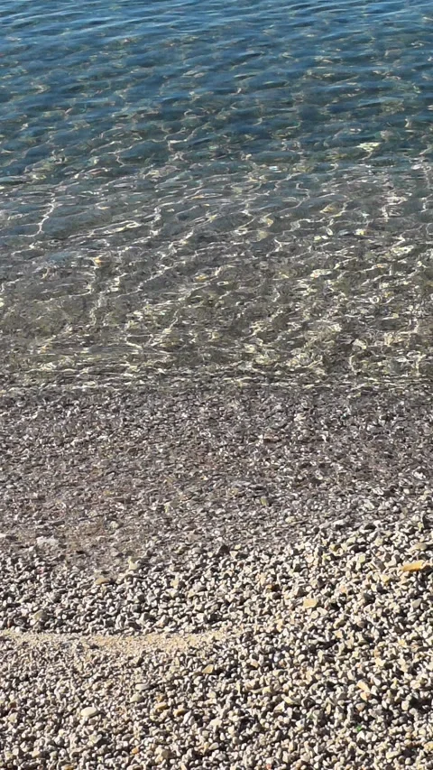 A pebble beach lapped by gentle waves Stock Footage 325622602