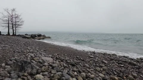 Pebble beach with small waves on Lake Geneva under cloudy sky Switzerland 库存影片 330744505