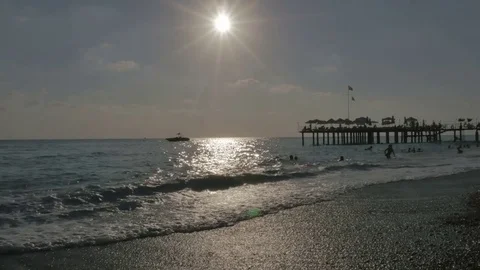 Pebble beach at sunset with floating people in the sea with big waves near the Video stock 80106499