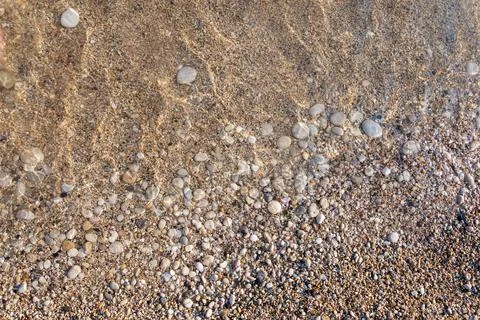 Pebble beach textured background. Close-up of crystal clear water with round Stock Photos