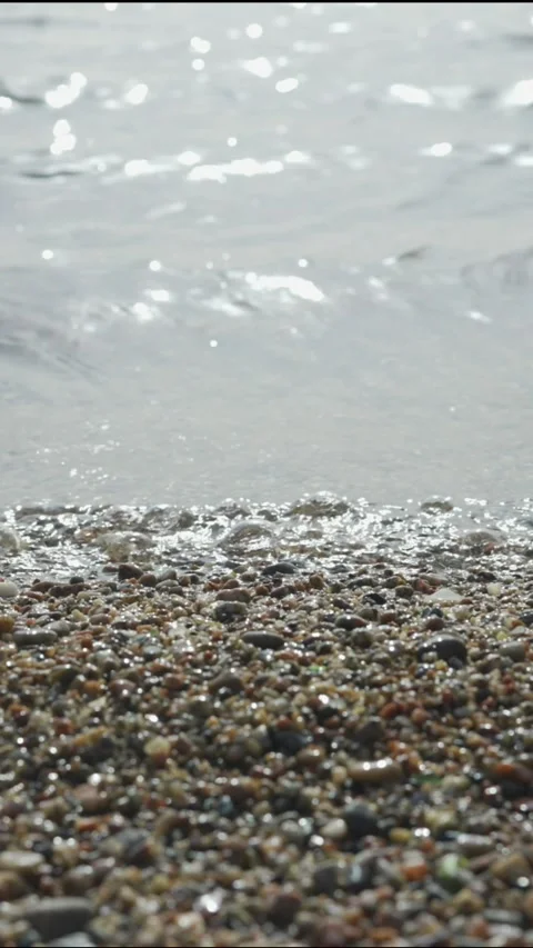 Pebble beach with transparent waves with sun glare on the water. Stock Footage 205810021