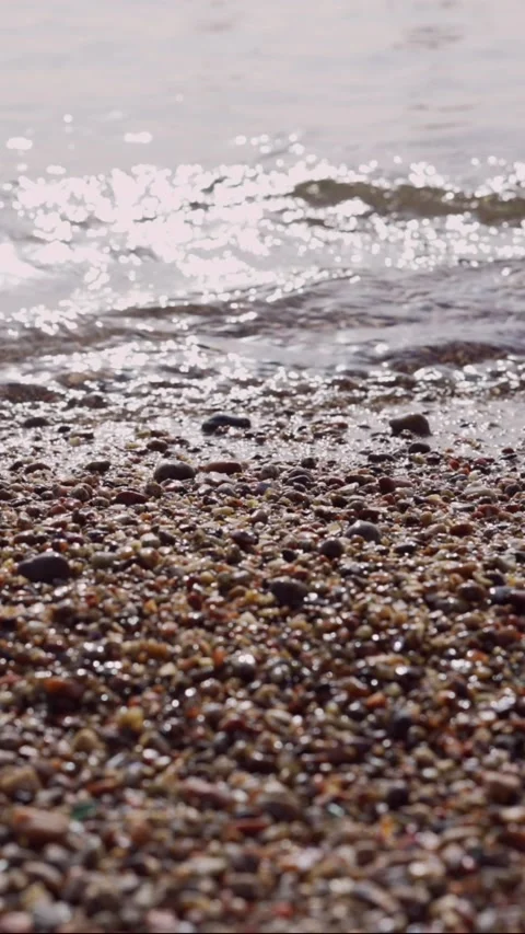 Pebble beach with transparent waves with sun glare on the water. Stock Footage 205813089