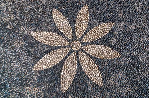 Pebble mosaic forming floral pattern on paved ground surface Stock Photos
