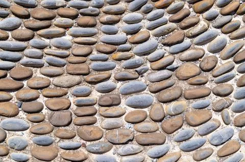 Pebble pavement arranged in curved pattern on tiled ground Stock Photos