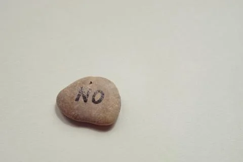 Pebble stone with text no on it at grey table. Copy space Foto stock