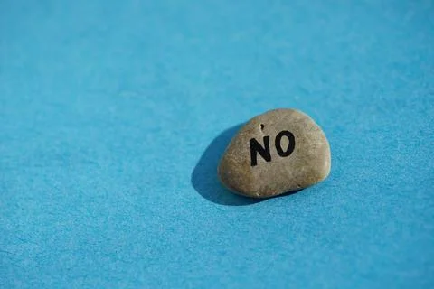 Pebble stone with text no on it on blue sunny table Stockfoto's
