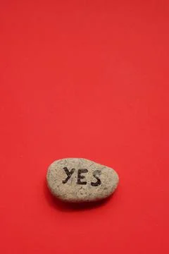 Pebble stone with text yes on it. Red background Фото