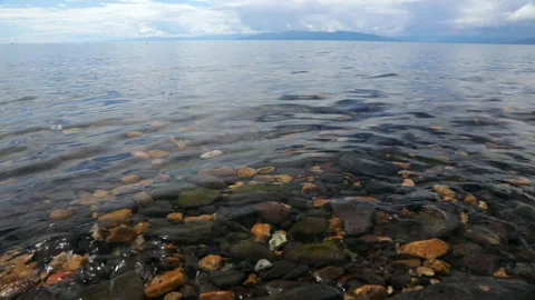 Pebbled lake bed seen through clear rippled water Stock Footage 276542843