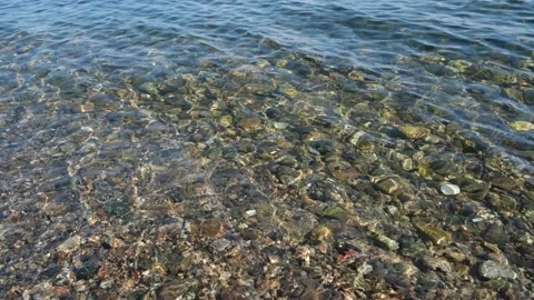 Pebbled lakebed seen through clear rippled lake Baikal transparent water natural Stock Footage 157381619