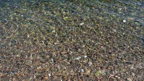 Pebbled lakebed seen through clear rippled transparent water background Stock Footage 157613703