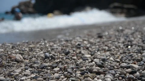 Pebbles against a blurred background of people playing at sea Stock Footage 111428576