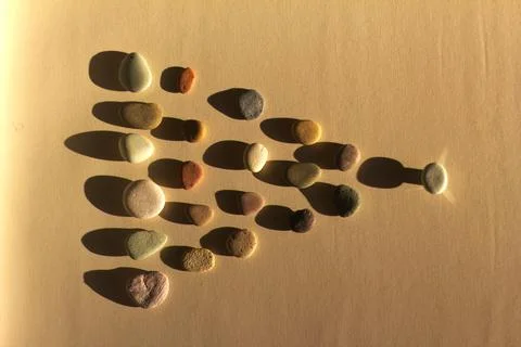 Pebbles Arranged in Arrow Shape with Dramatic Long Shadows Stock-Fotos