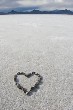 Pebbles arranged on salt flat in the shape of a heart. Stock Photos
