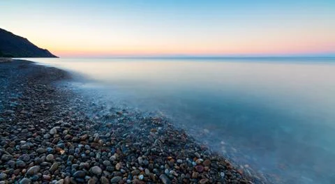 Pebbles on a beach causing the sea to flow around them making patterns Foto stock