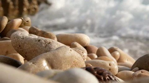 Pebbles on beach close up and waves crashing shore Stock Footage