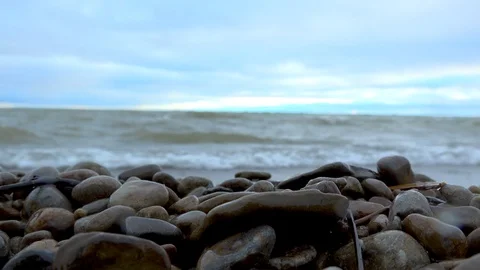 Pebbles on beach as waves break on the shore in background Stock Footage 94598750