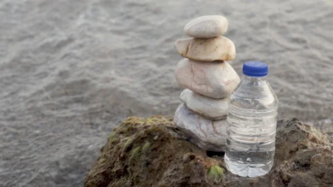 Pebbles in pyramid one over another and bottle with drinking water Stock Footage 218836723