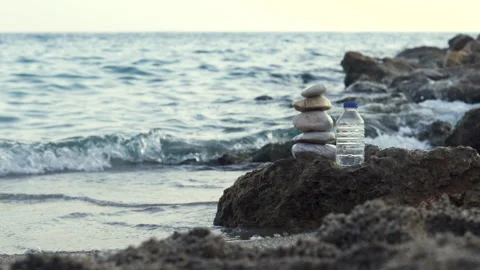 Pebbles in pyramid one over another and bottle with drinking water Video stock 218962924