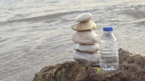 Pebbles in pyramid one over another and bottle with drinking water Stock Footage 222001178
