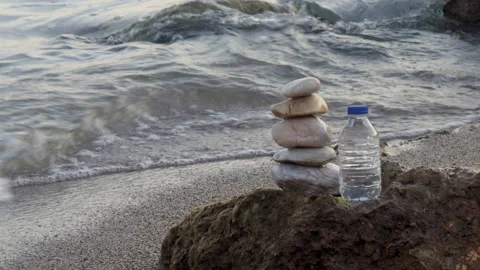Pebbles in pyramid one over another and bottle with drinking water Vídeo Stock 222001180