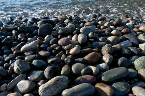 Pebbles on the seashore as an abstract background. Stock Photos