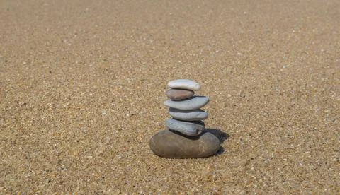 Pebbles stacked on a sandy beach background Stock Photos