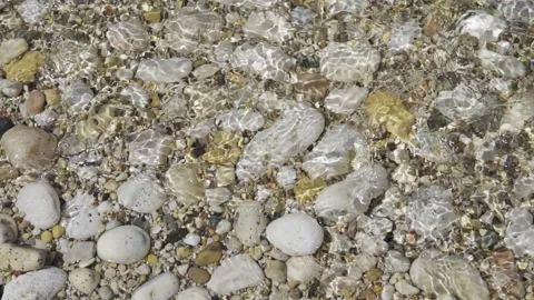 Pebbles in water, top view, close-up. Pebble beach. The water washes the stones. Stock Footage 156725724