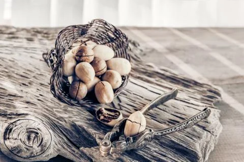 Pecan and macadamia nuts with a device for chopping nuts on a wooden backgrou Stock Photos