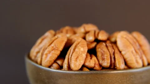 Pecan nut in a brown cup on a dark brown background. Rotation. Video stock 157042249