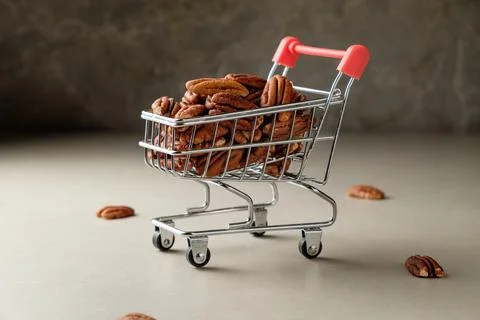 Pecan nuts overflowing in a tiny shopping cart under soft ambient light Stock Photos