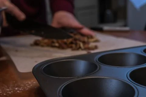 Pecans being chopped in the background of a muffin tray Stock Photos