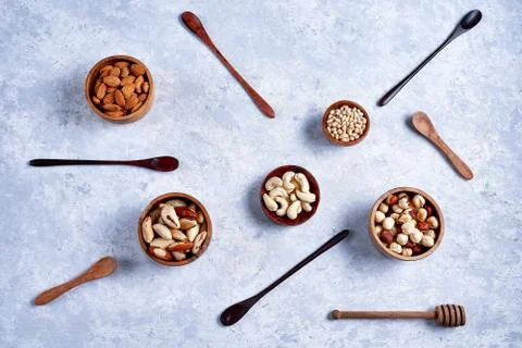 Pecans, hazelnuts, almonds, pine nuts, cashews in wooden bowls on blue backgr Stock Photos