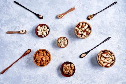 Pecans, hazelnuts, almonds, pine nuts, cashews in wooden bowls on blue backgr 库存照片