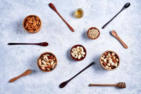 Pecans, hazelnuts, almonds, pine nuts, cashews in wooden bowls on blue backgr Stock Photos