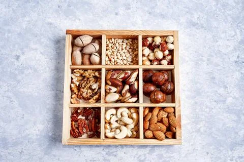 Pecans, hazelnuts, almonds, pine nuts, brazil nut, cashews in a wooden box on Fotos Stock