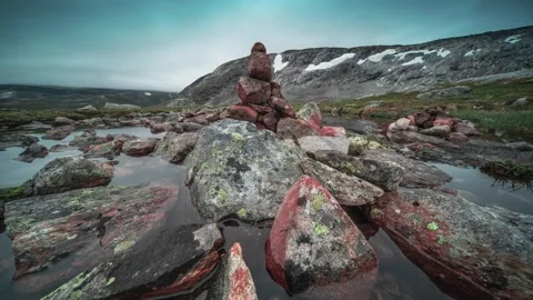 Peculiar stone cairns stand on lichen-covered rocks and are surrounded by Stock Footage 270073754