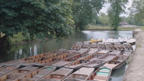 Pedal-boat floats past moored punts down Oxford river. Stock Footage 91001553