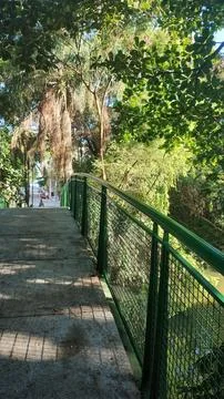 Pedestrian bridge with green railing in a park Stock Photos