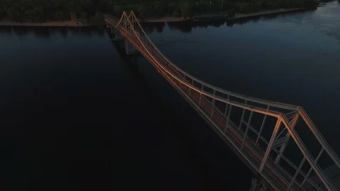 Pedestrian bridge over the river near the city at sunset aerial drone shoot Stock Footage 90363853