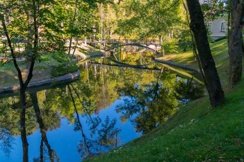 The pedestrian bridge in the park is reflected in the layout of a calm river Stock Photos
