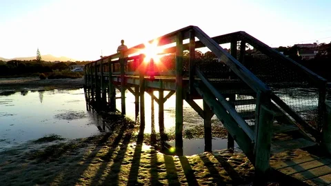 Pedestrian bridge at sunset with man walking over it. Scamander, Tasmania Stock-Footage 71445682