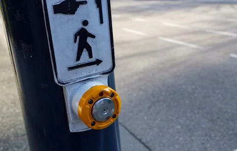 Pedestrian crossing button with yellow push mechanism and directional sign .. Stock Photos