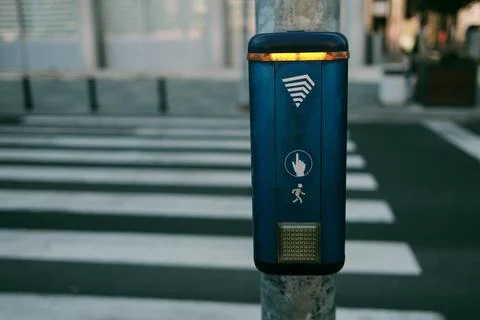 Pedestrian crossing control button standing beside a zebra crossing on an urb Stock Photos