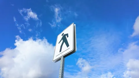 Pedestrian crossing sign against a vibrant blue sky with scattered clouds Stock Footage 321672953