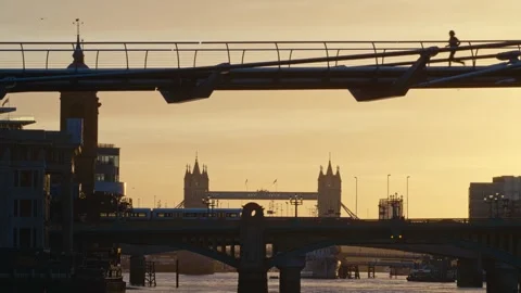 Pedestrian jogging across the Millennium Bridge in early morning in Stock Footage 257516522