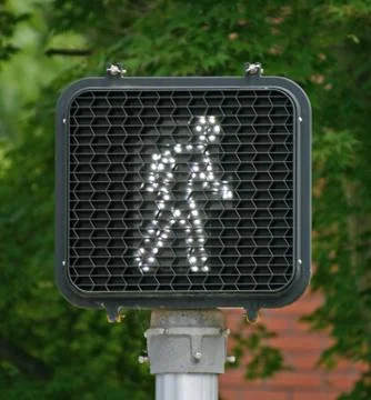 A pedestrian light indicating it is safe to cross the street Stock Photos