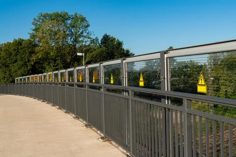 Pedestrian pathway features multiple warning signs along its railing Stock Photos