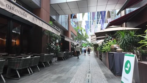 A pedestrian walkway lined with greenery and potted plants leads through a Stock Footage 287001236