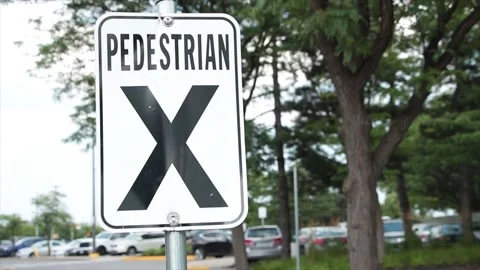 Pedestrian x vertical rectangle white black sign on metal post with parking lot Stock Footage 249754758